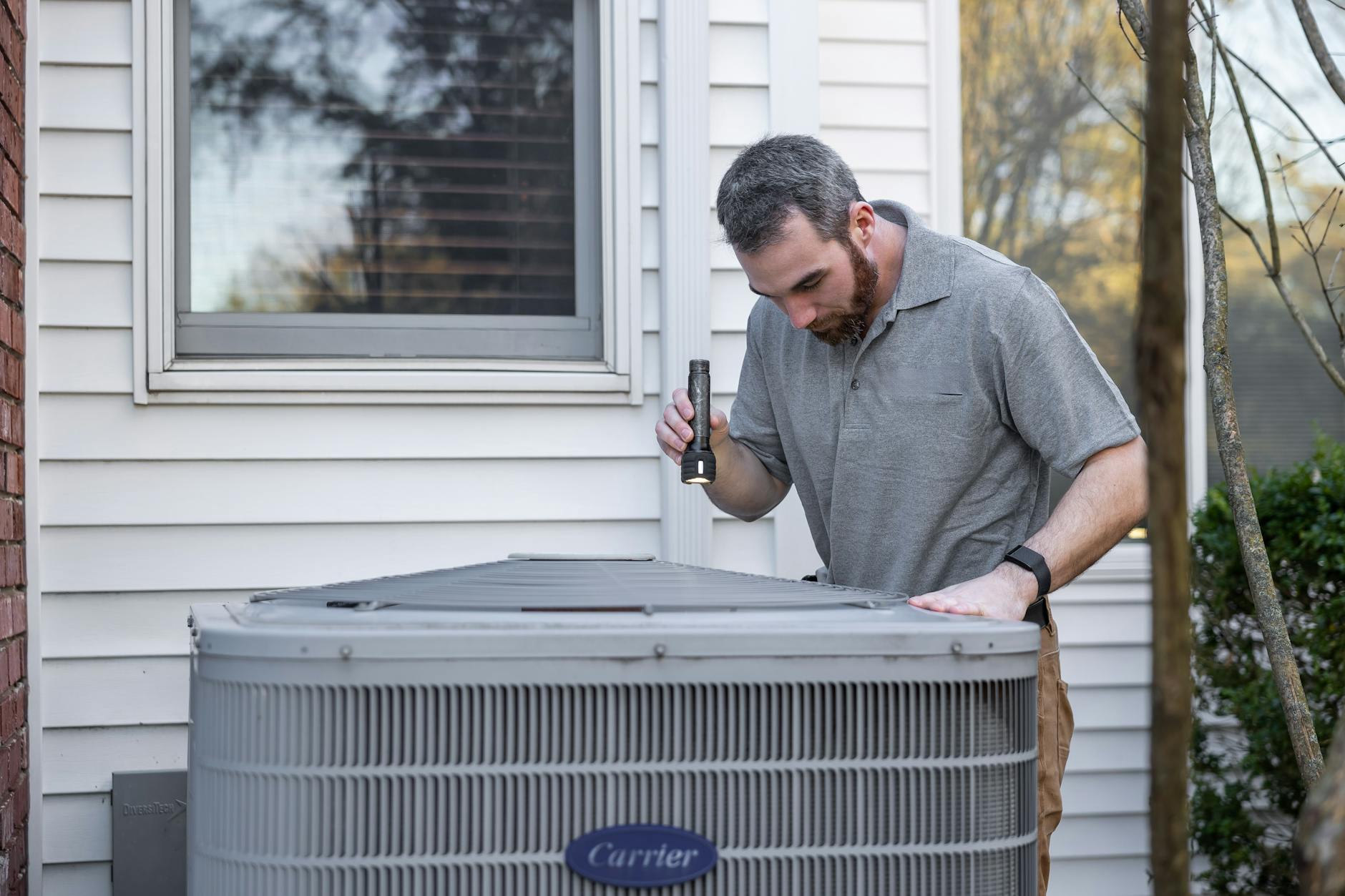 HVAC technician inspecting an outdoor air conditioning condenser unit